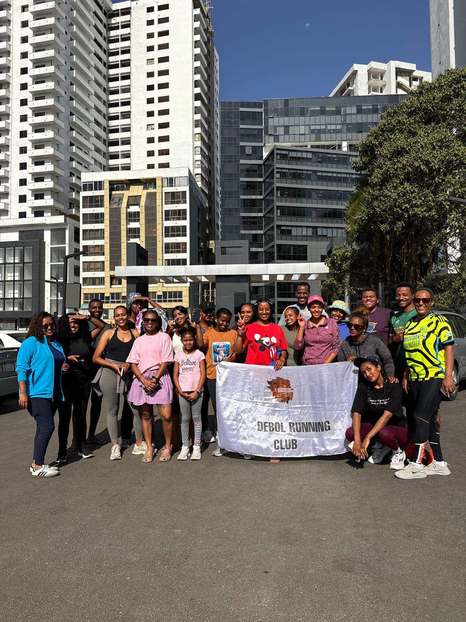 The DEBOL Running Club gathered behind the club banner after a run, Addis Ababa behind them