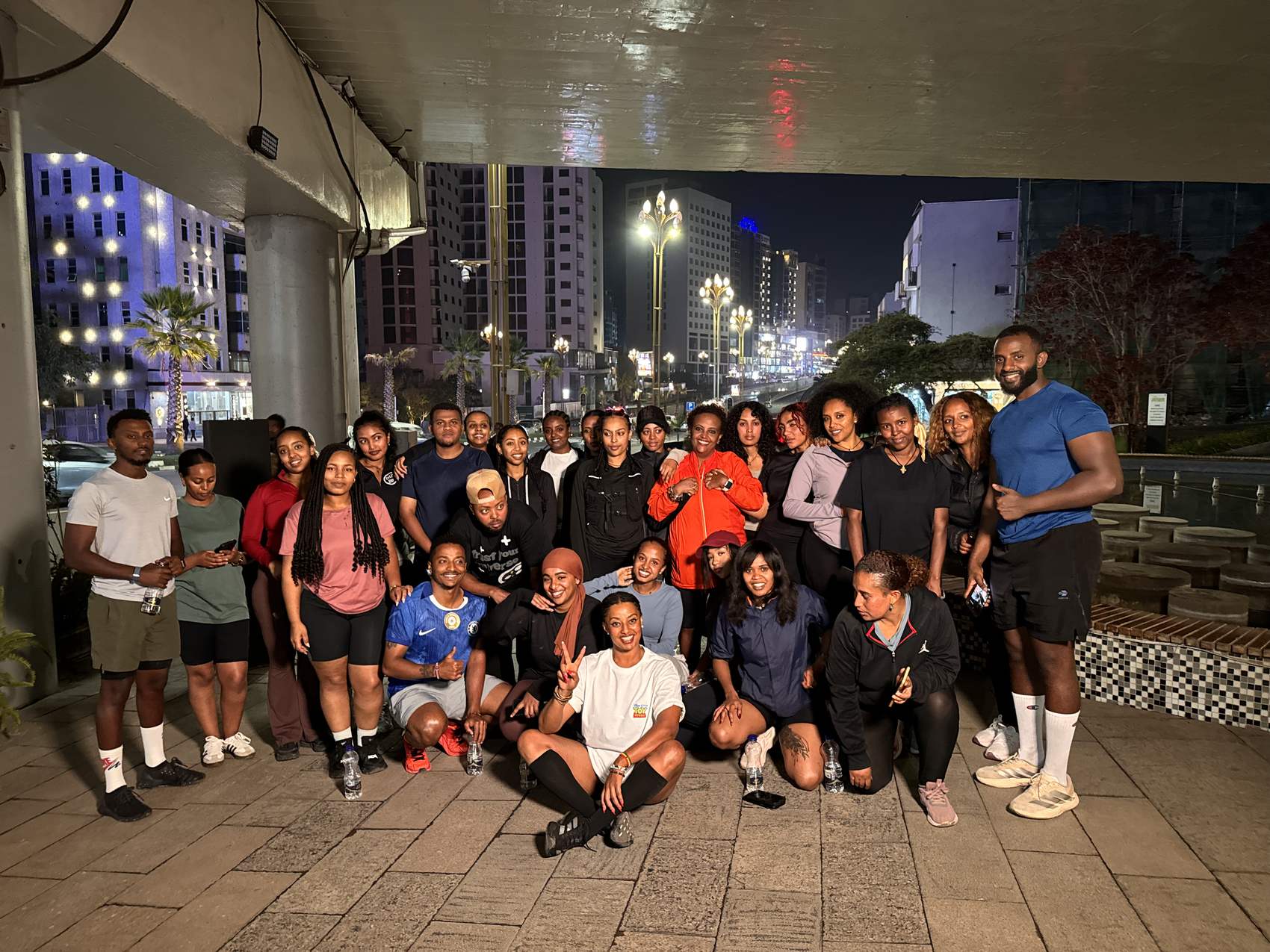 The group gathered under the bridge at night, the lit city behind them