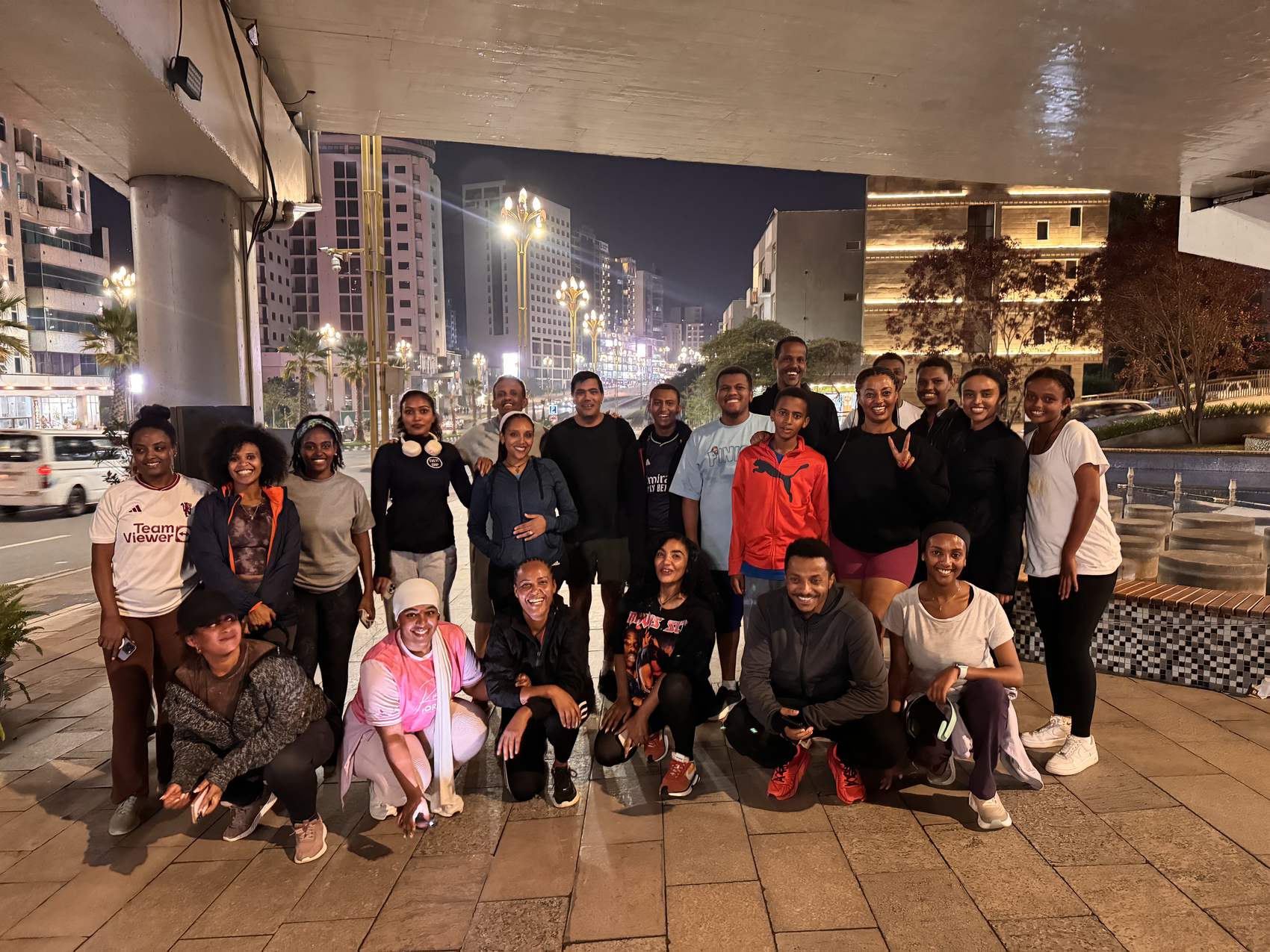 The club posing together on the pavement after an evening run, lit city streets behind them