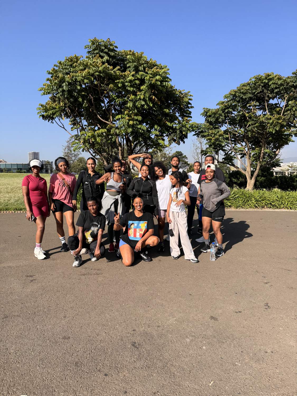 The club standing together under a tree at the park after a morning run