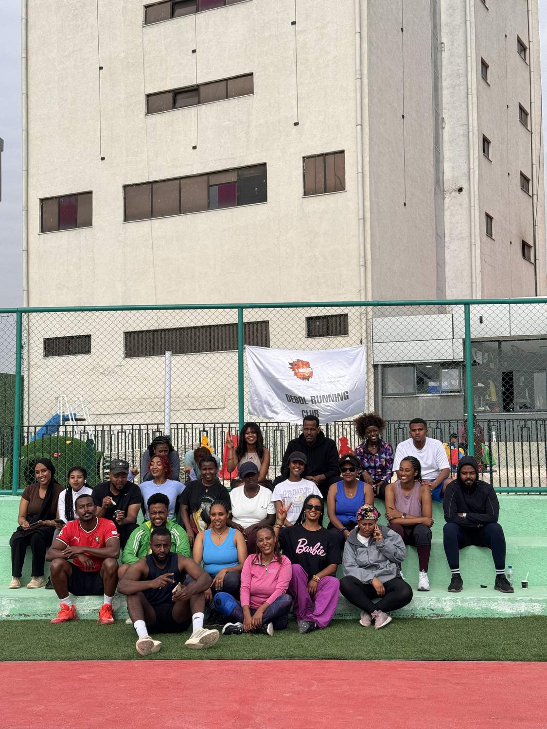 Members sitting together on the pitch beneath the Debol Running Club banner